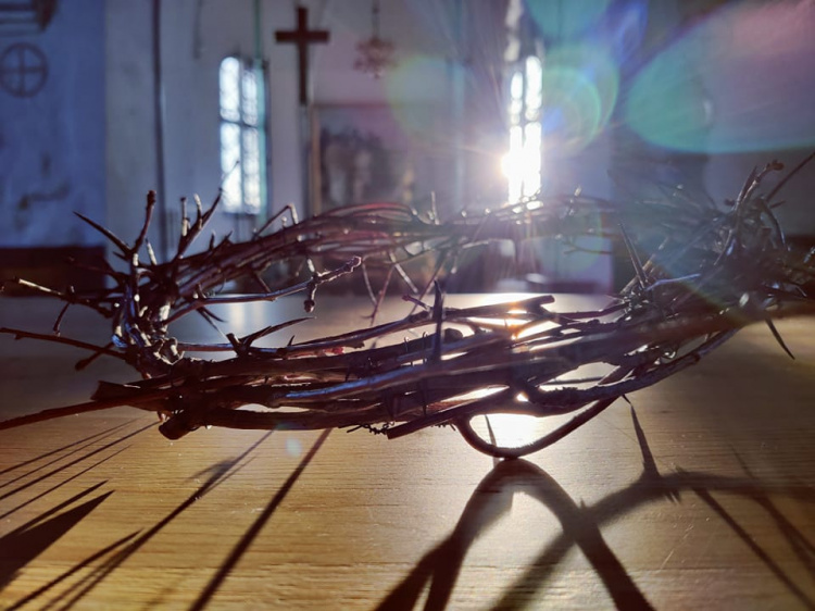 Orjantappurakruunu lähikuvassa sekä valoja ja varjoja ja taustalla Liedon kirkon sisätilaa. 
