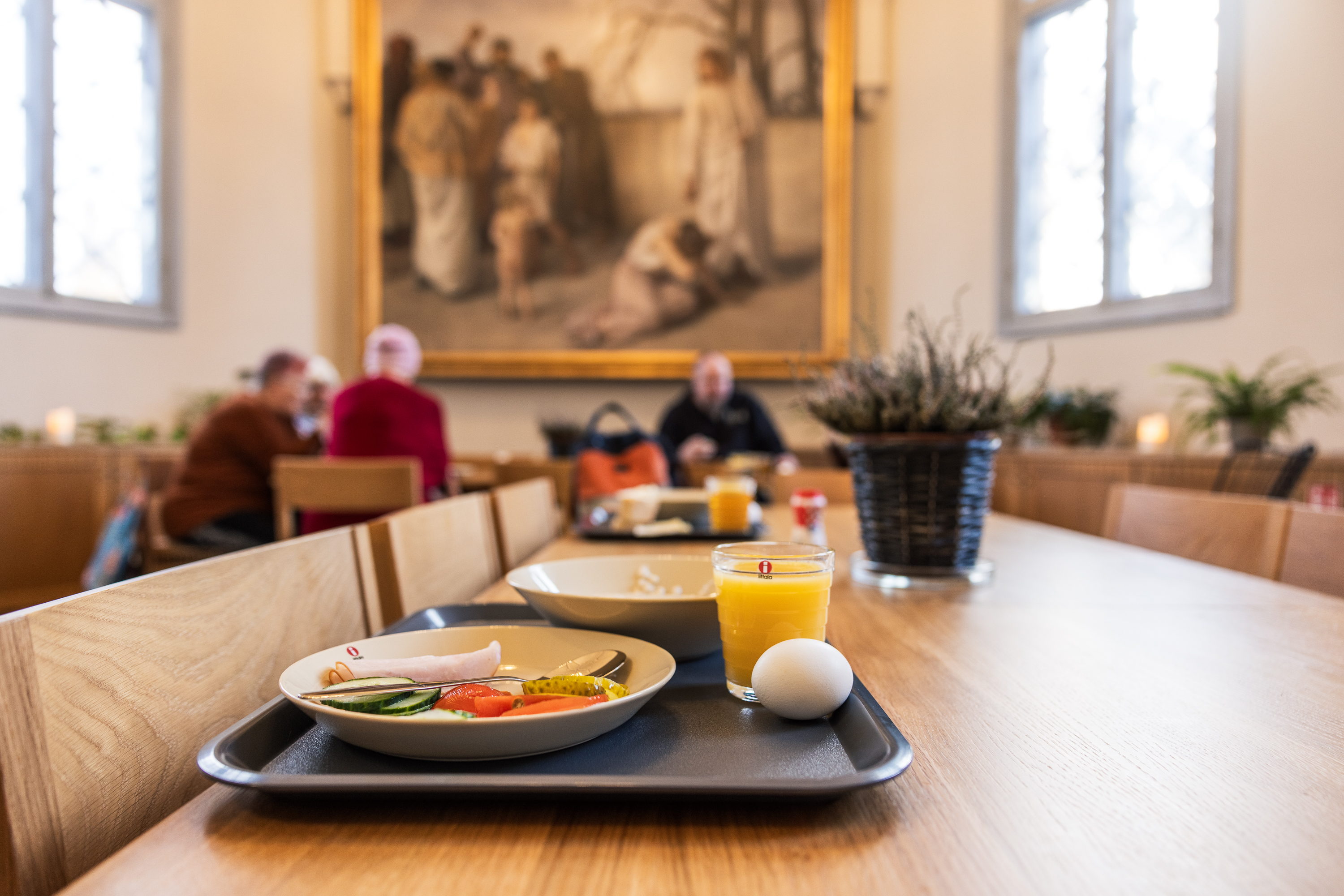 Lautasella aamiaista ja taustalla ruokailijoita kirkossa.  