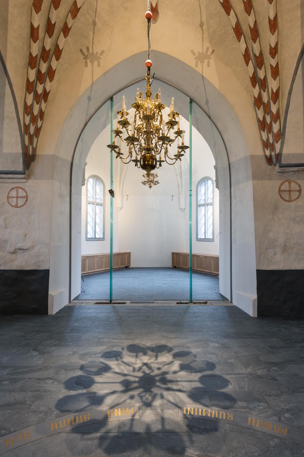Liedon kirkon kirkkosalista näkymä pikkukirkkoon ja näiden välissä lasiovet sekä etualalla vaskikruunu.