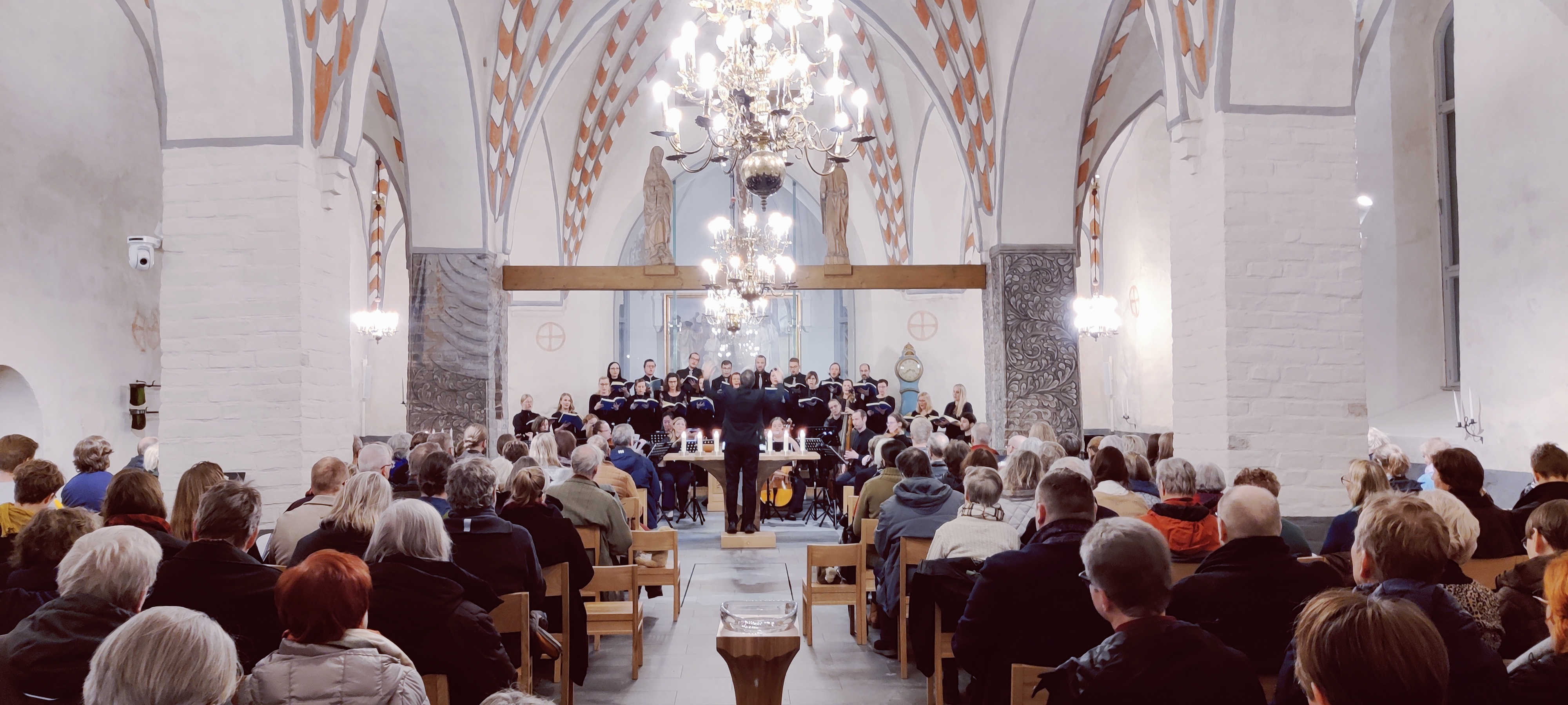 Kuoro konsertoimassa kuulijoita täynnä olevassa Liedon kirkossa.