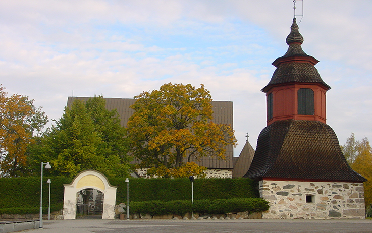 Kellotapuli kuvassa oikealla kirkon pysäköintialueelta kuvattuna ja vasemmalla vanha hautausmaan portti.