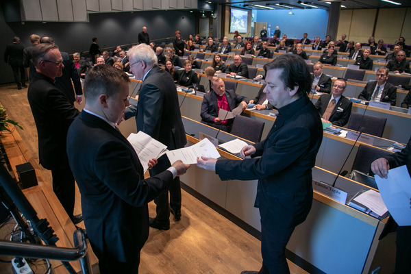 Kirkolliskokouksen yleiskuvassa etualalla varapuheenjohtajat ja materiaalin jakoa.