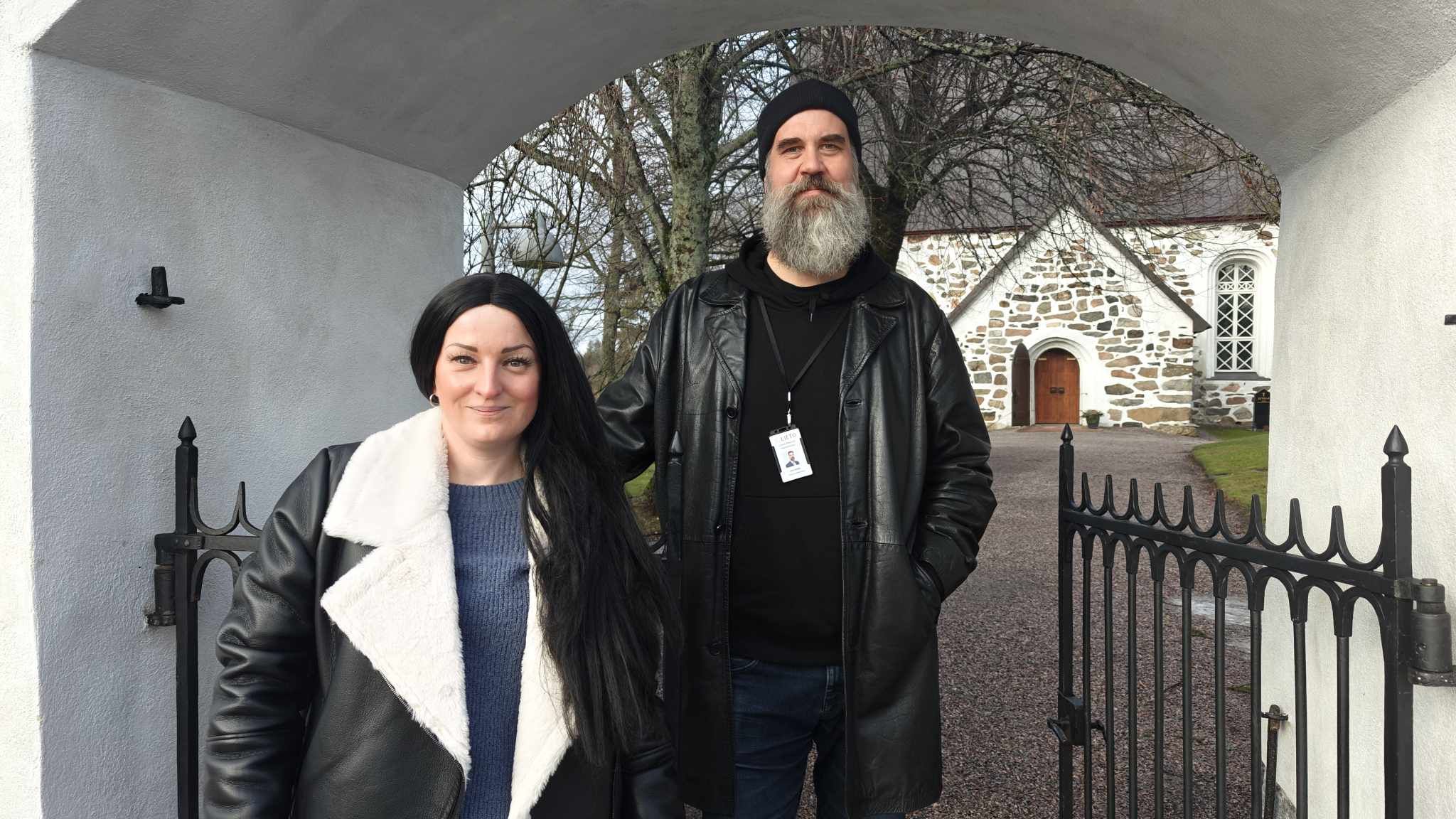 Yvonne Smidtslund-Hissa ja Jani Äijälä Liedon kirkon portilla. Taustalla Liedon kirkko. Taustalla hautausma...