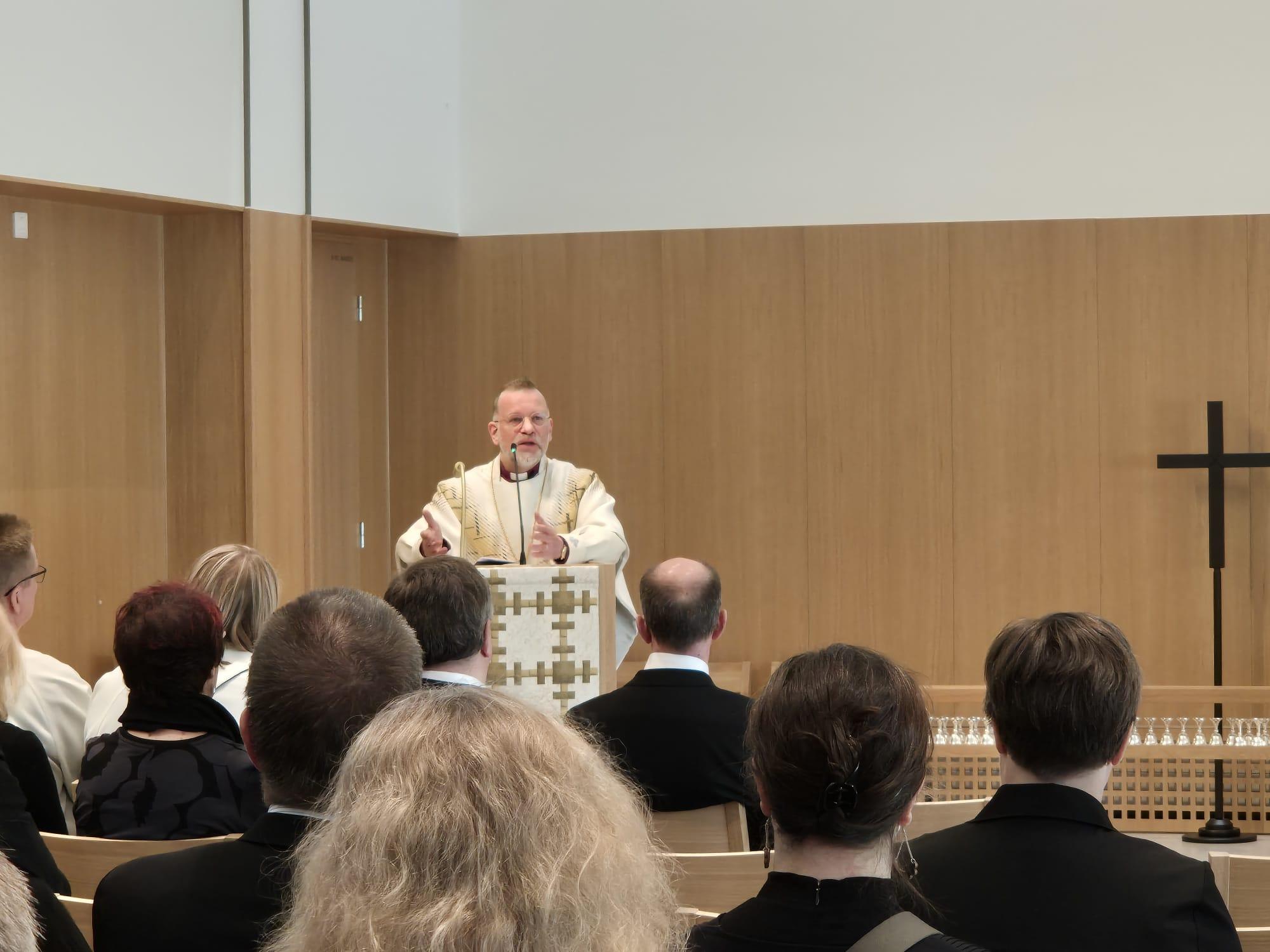 Piispa Jari Jolkkonen ja ihmisiä kuuntelemassa häntä.