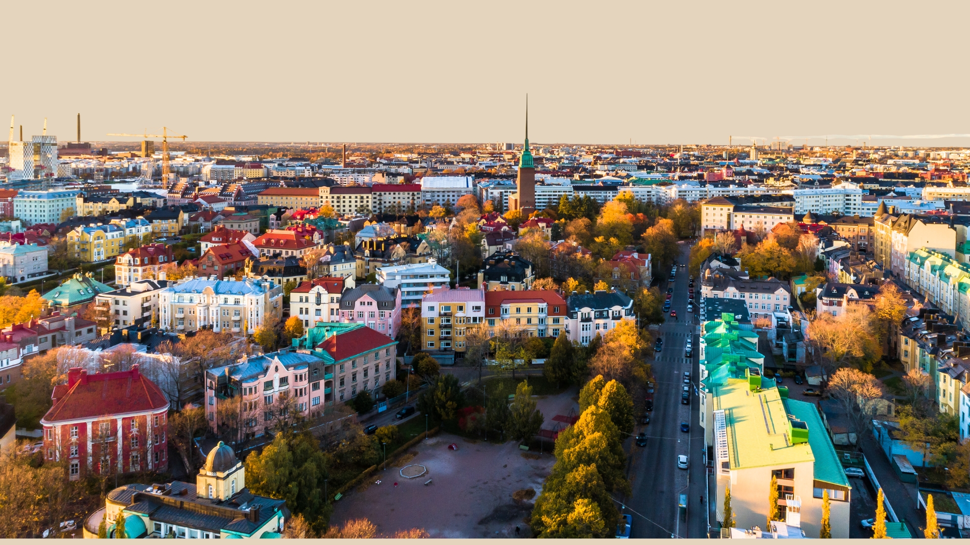 Kaupunkinäkymässä eri värisiä ja eri aikakauden rakennuksia, pääosassa kerrostaloja, kirkko.