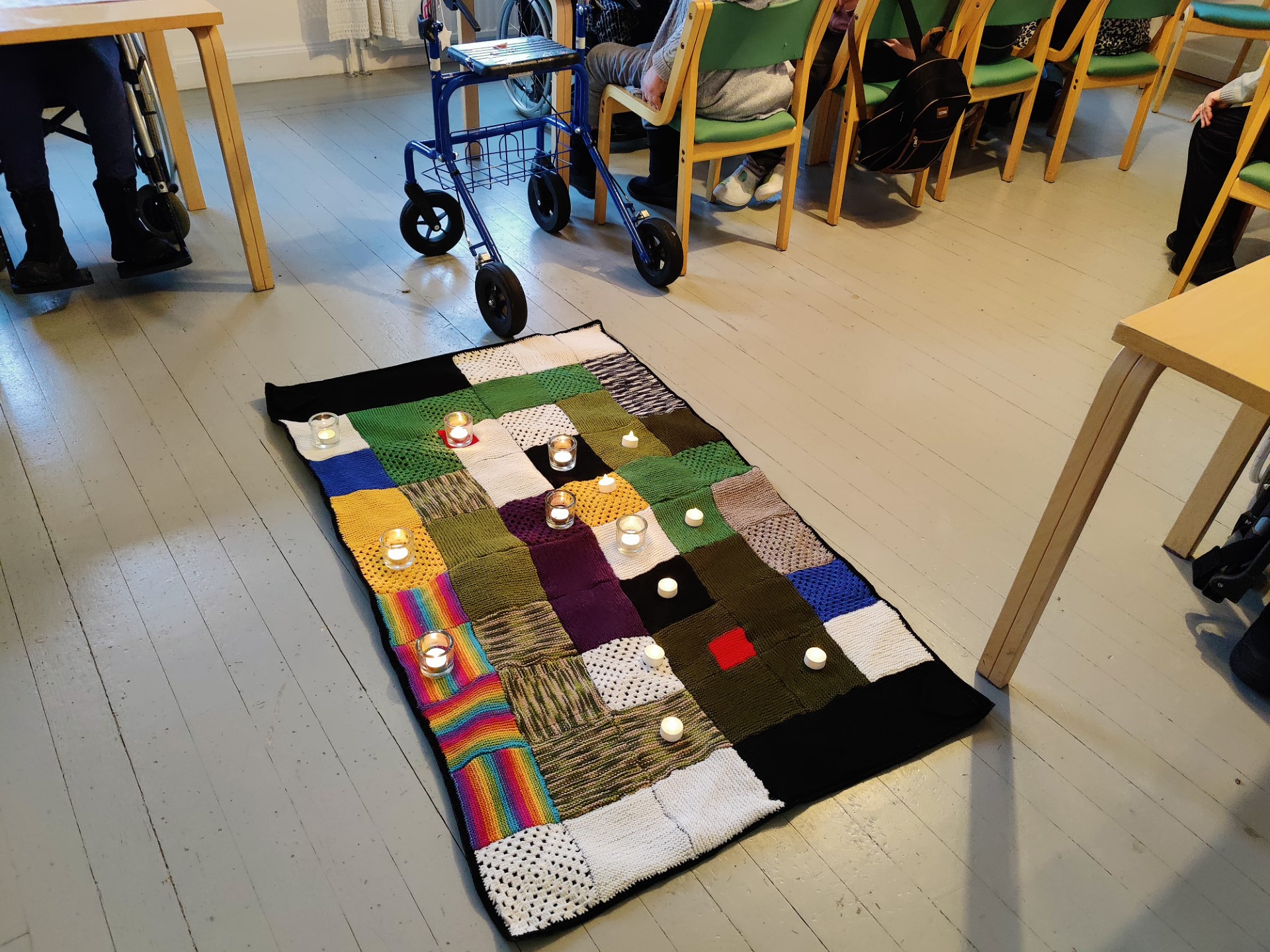 Puulattilalla tilkkupeitto ja peiton päällä ledkynttilät.