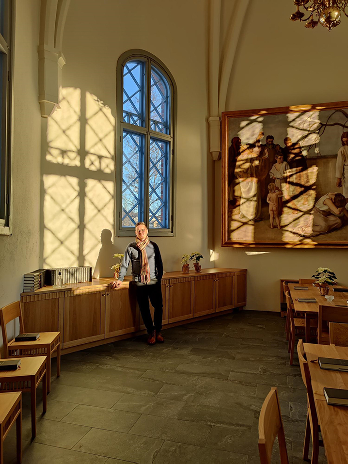 Kirkkoherra Risto Leppänen seisoo Liedon kirkon itäpäädyn pikkukirkossa kaappiin nojaten auringonvalon heij...