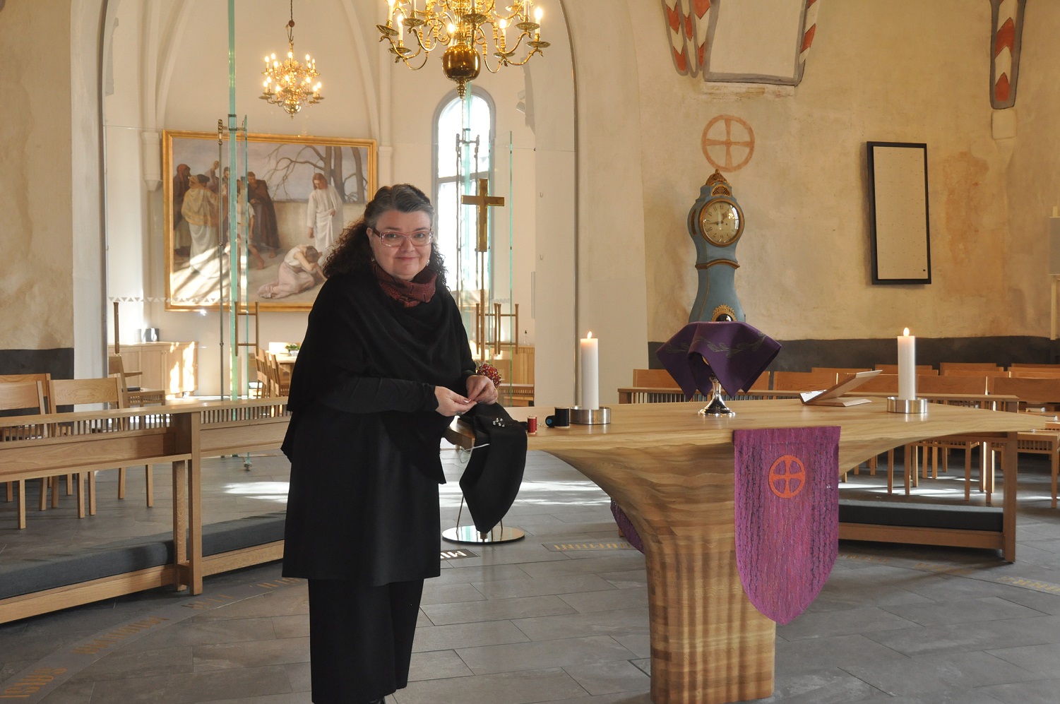 Tekstiilitaiteilija Helena Vaari Liedon kirkossa alttarilla sommittelemassa tekstiilejä.