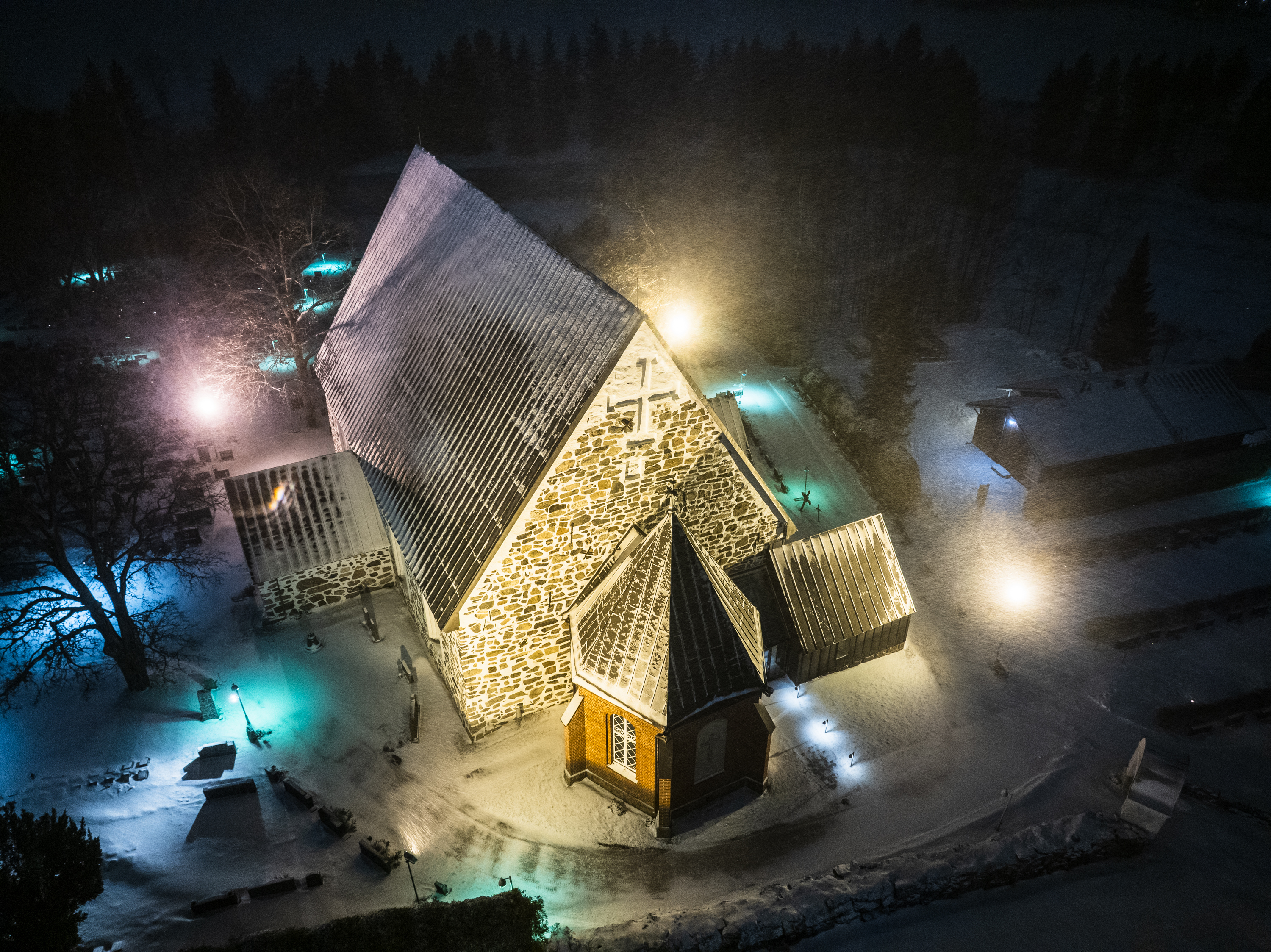 Liedon kirkko hiukan lumisessa yöllisessä maisemassa. 