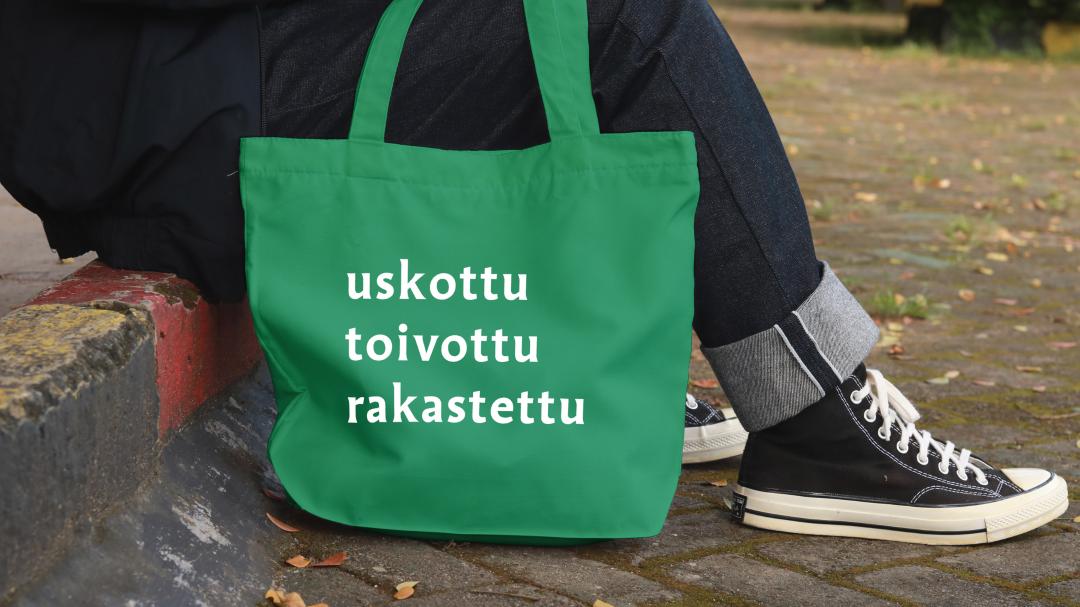 Vihreä kangaskassi, jossa valkoisella sanat 