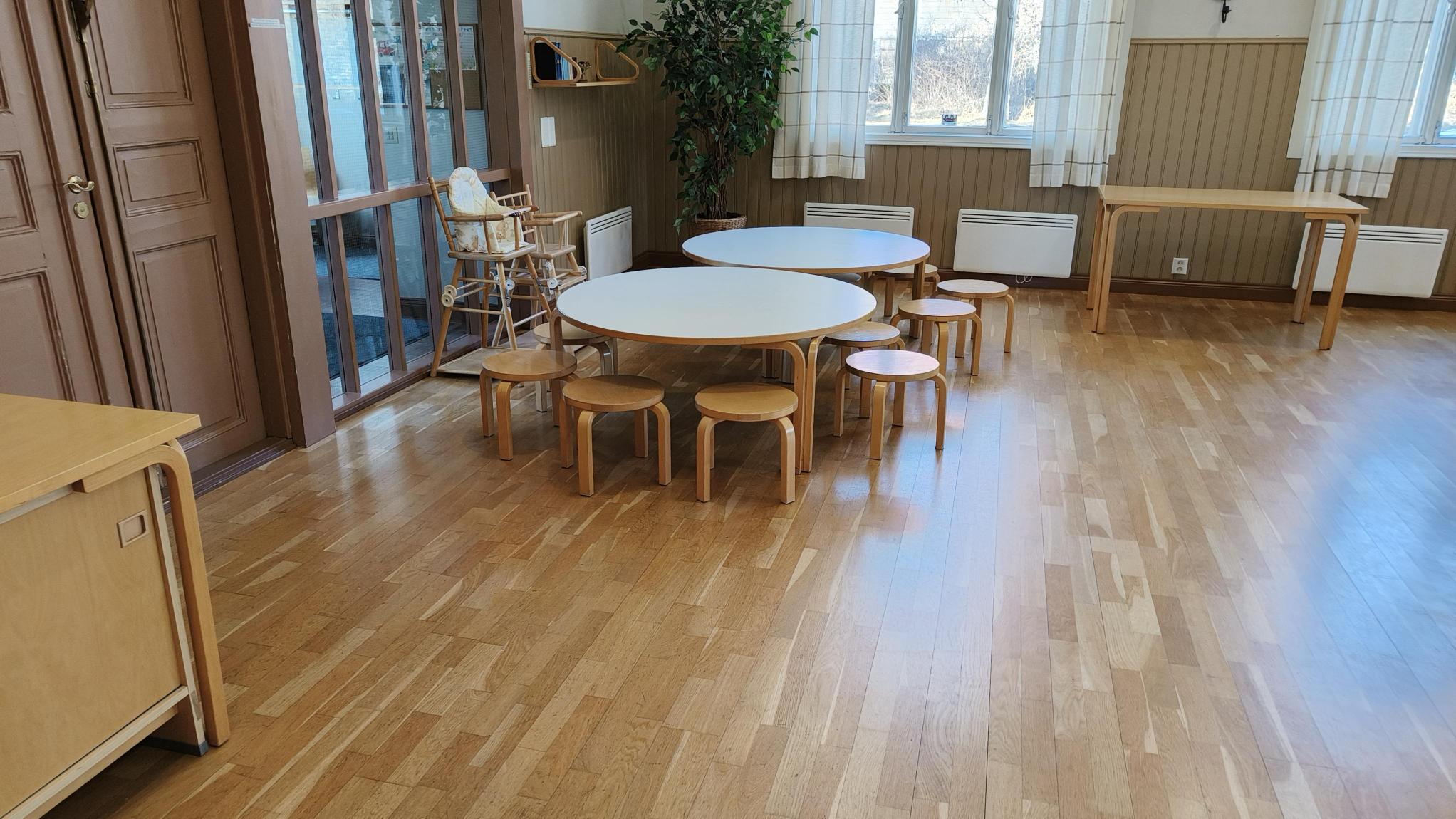 Sali, lastenkalusteita, parkettilattiaa, korkeat ikkunat.